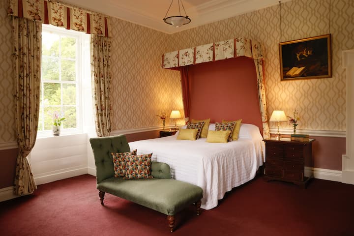 La habitación rosa en el primer piso tiene una magnífica cama tamaño king (6 pies x 6 pies) y baño en suite con ducha a ras de suelo. Tiene ventanas al este y al norte con vistas a la parte delantera de la casa. 