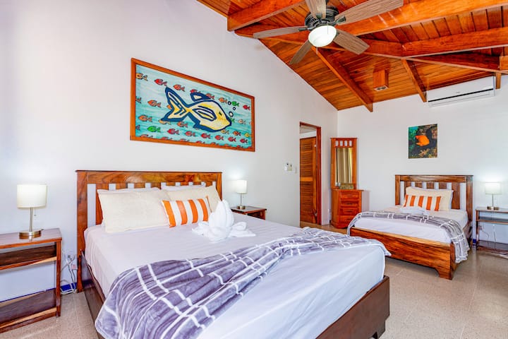 This upper-floor bedroom offers ocean views and a private balcony. It features a queen bed, a twin bed, and an ensuite bathroom. Accommodates up to 3 guests.