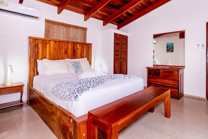 This inviting bedroom in Villa Olivia features a queen bed and an ensuite bathroom. It opens into a tranquil courtyard, providing a peaceful retreat for two guests.