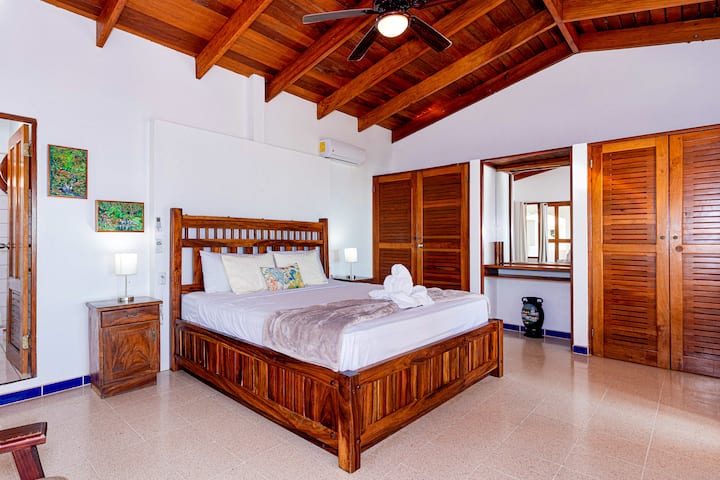 This spacious upper-floor bedroom features a king-sized bed, an en-suite bathroom, and a balcony with stunning ocean views.