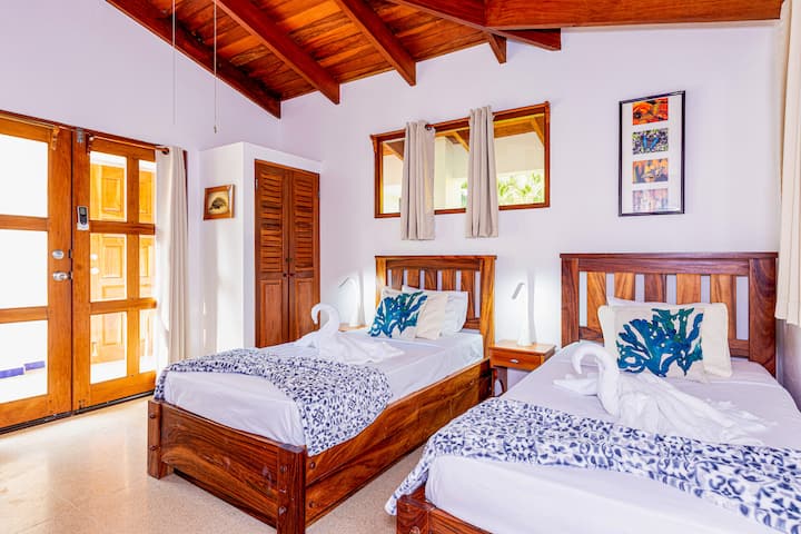 This cozy bedroom accommodates two guests with twin beds and an ensuite bathroom. It opens into a charming courtyard, offering a serene outdoor retreat.