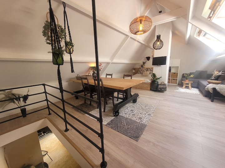 Étage supérieur spacieux avec une grande table à manger, un lit double et un coin salon