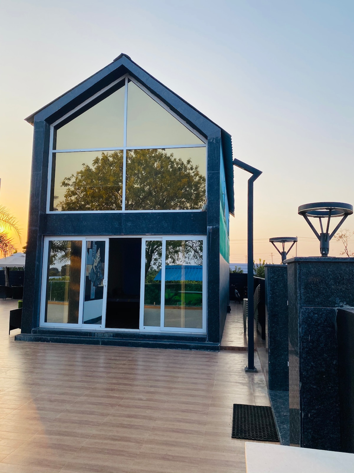 A modern structure with a prominent A-frame design is depicted, featuring large glass panels that provide extensive natural light. The sleek exterior is complemented by a well-maintained patio area, creating a harmonious connection between indoor and outdoor spaces.