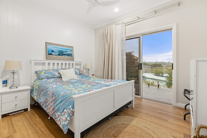 Bedroom 1, with a comfortable queen-size bed, boasts ocean views and direct deck access via a sliding glass door. Enjoy the breeze with a ceiling fan and benefit from ample storage.