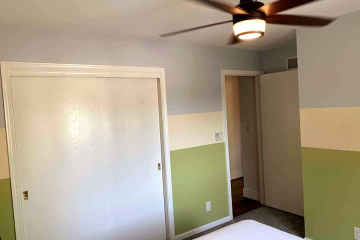 Ლამაზი დიდი კარადა მეორე საძინებელში მლაშე ჭერის ვენტილატორის ქვეშ კომფორტისთვის.