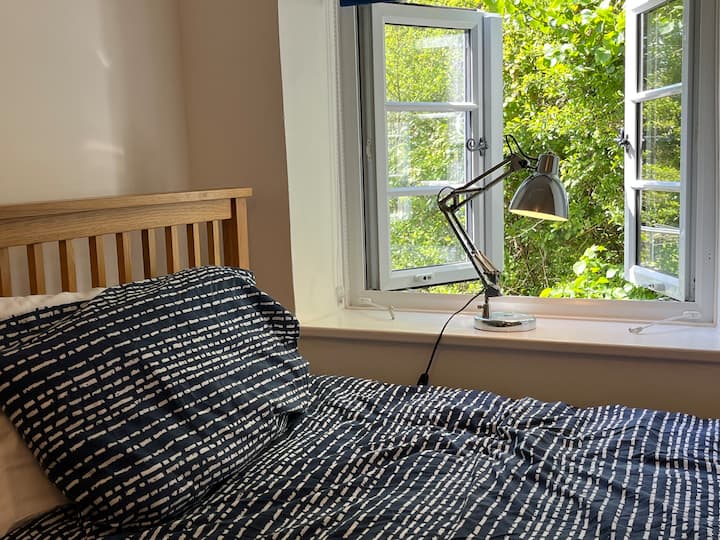 El dormitorio individual tiene vistas al jardín y al follaje del bosque y a una unidad de almacenamiento para tus pertenencias.