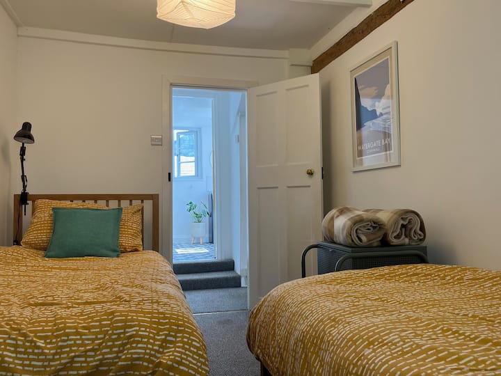 La habitación doble tiene dos camas individuales y dos unidades de almacenamiento. Las obras de arte costeras y el techo con vigas garantizan que este sea un espacio de descanso.