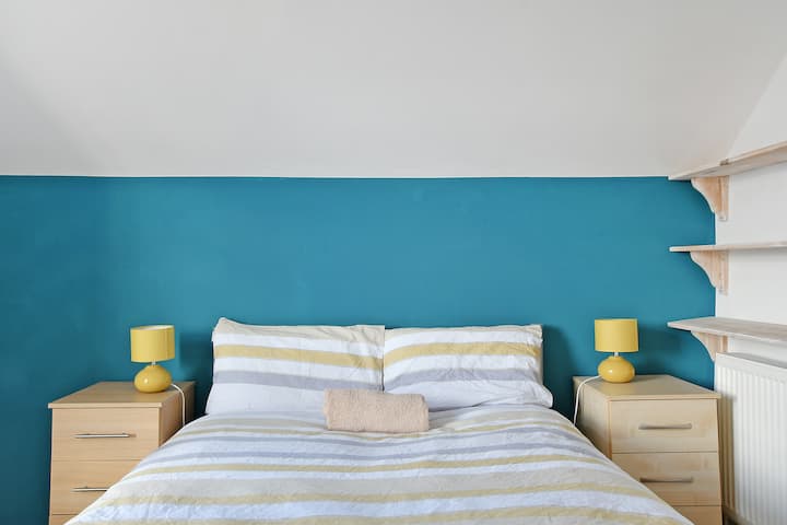 Gezellige slaapkamer met levendige hoofdeinde muur, perfect voor een ontspannen verblijf.