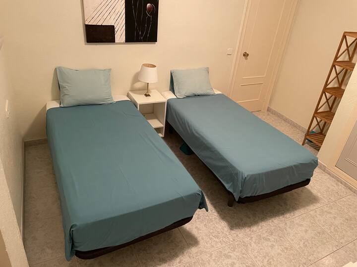ห้องพักพร้อมเตียงเดี่ยว 2 เตียงพร้อมพัดลมเพดาน  หน้าต่างพร้อมชัตเตอร์ลูกกลิ้งไฟฟ้า