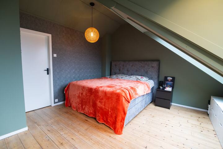 Chambre avec sommier double au sol mansardé avec une buanderie attenante avec sèche-linge et lave-linge et une deuxième salle de bain communicante avec WC et douche.