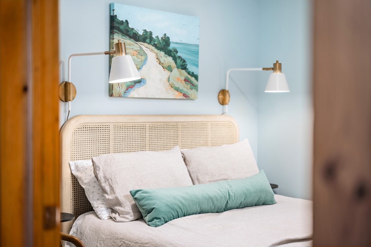 Esta cama tamaño queen está coronada con hermosas sábanas de primera calidad y rodeada de hermosas obras de arte de un artista local del norte de Michigan y muebles y decoración completamente nuevos.