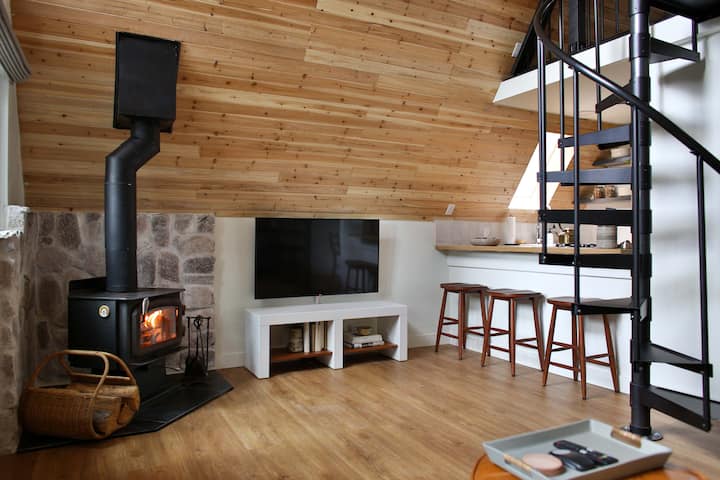 The comfy main level living space with smart TV and cozy wood stove. Stairs lead to the upper level sleeping area