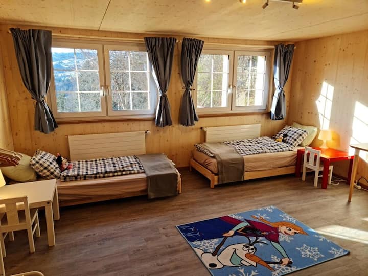 Grosses Kinderzimmer mit 3 Einzelbetten 1 Babyreisebett, Wickeltisch, Kindertischen und Bürotisch mit Stuhl (neu renoviert 2022). Die Betten  sind zwar gross genug für Erwachsene, allerdings ist das Zimmer als Kinderzimmer eingerichtet.