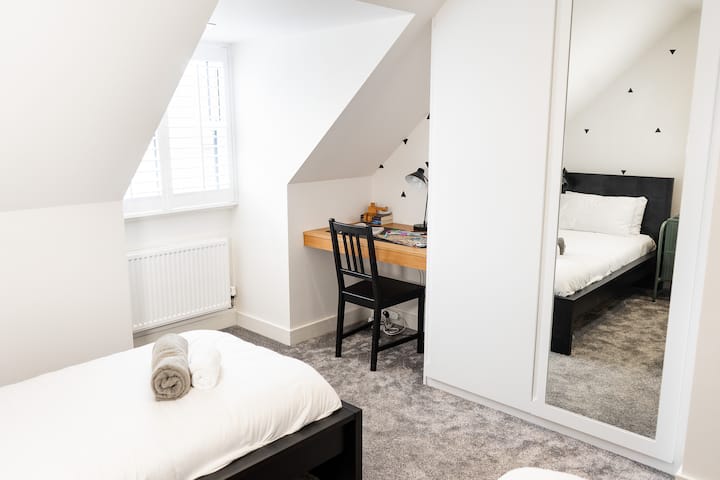 二楼卧室，内置衣柜和可爱的角落书桌空间，窗户上有百叶窗