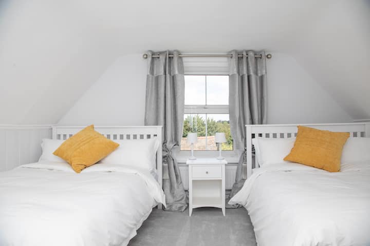 Jedna z dvoch podkrovných spální s dvoma manželskými posteľami na druhom poschodí, ktorá má spoločnú kúpeľňu s druhou.