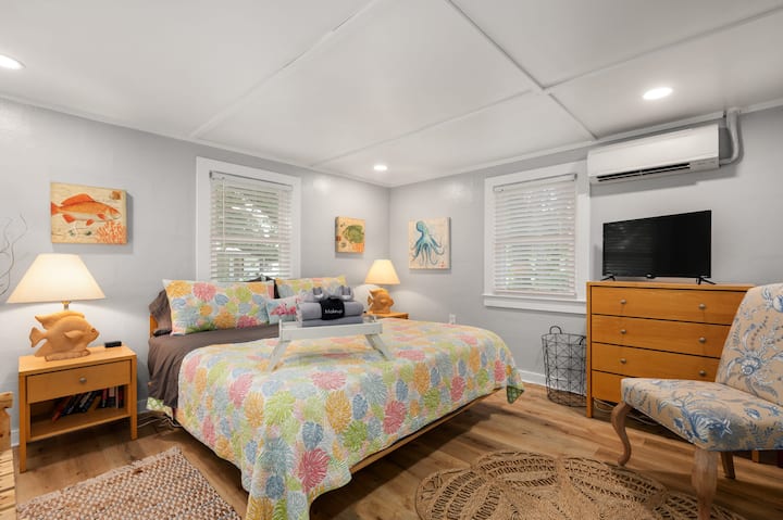 King bed with smart television and charging stations at each bedside. Dresser drawers, bench and luggage rack