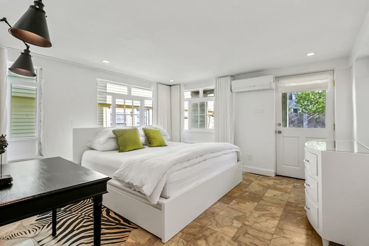 The bedroom is wrapped in custom linen black-out curtains and features a king-sized bed with memory foam mattress, writing desk, and under-bed storage, dresser, and hotel-style clothes-hanging system. 