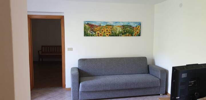 غرفة معيشة في الطابق الثاني بسرير أريكة وتلفزيون وباب للدخول إلى الشرفة.