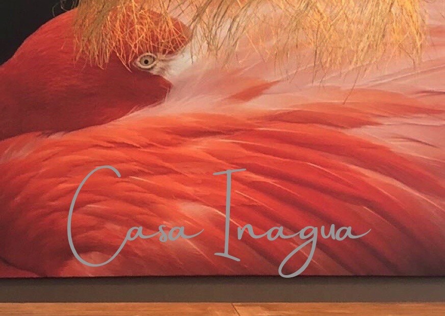 A striking mural features a close-up of a vibrant flamingo, displaying its soft, feathered plumage in shades of orange and pink. The artwork is complemented by natural materials, creating an intriguing focal point in the space.