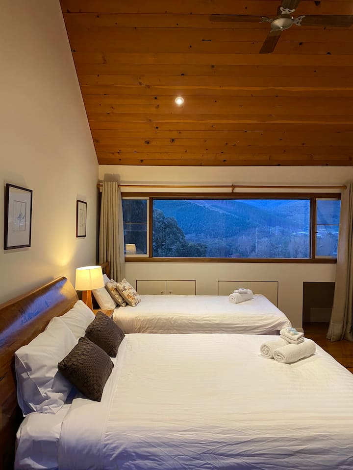 Large queen bed and single bedroom in 3rd upstairs bedroom with walk in robe and small balcony. Alpine valley views on one side views to the forest on the other. Possible additional trundle in this room can make it a family room. Small desk included.