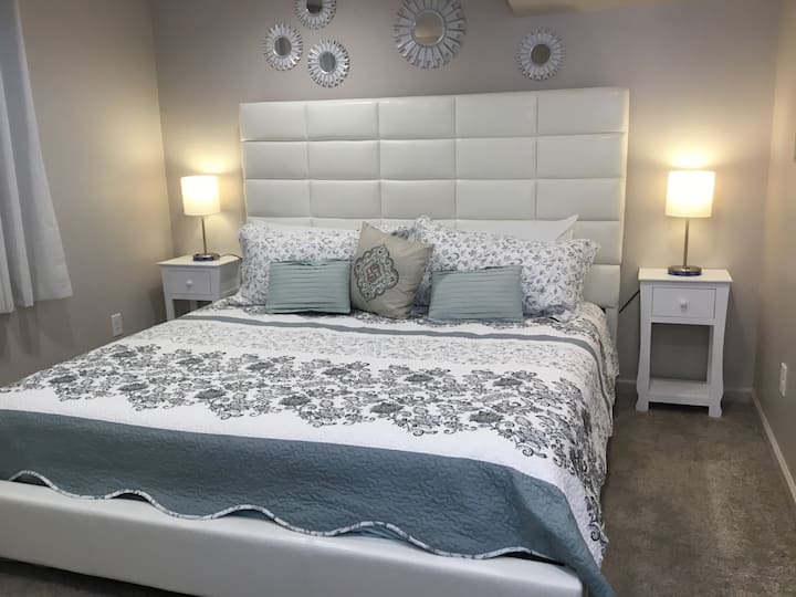 Master Bedroom - Beautifully decorated with King size hybrid bed, reading corner, closet with hangers, luggage rack, lamps with phone chargers, and full length mirror.