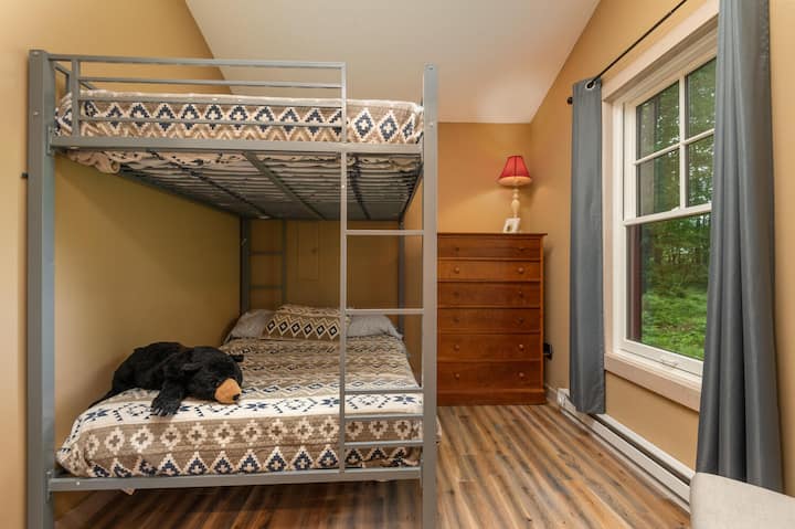 Habitación con literas divertida y funcional con un ambiente acogedor de bosque, ideal para niños o huéspedes adicionales.