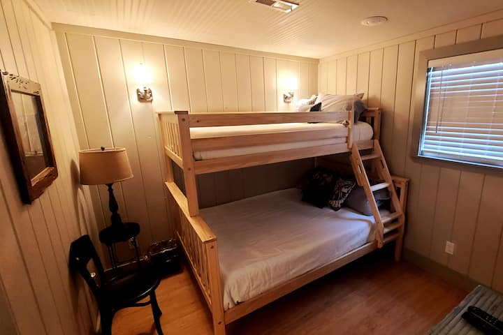 View of the spare bedroom of the Chef's Cottage with a twin/full bunk bed, big-screen TV, and half bath.