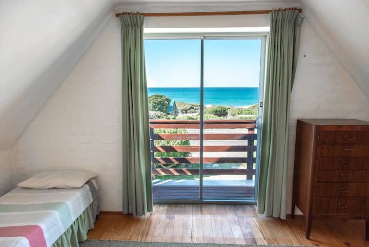 غرفة نوم في الطابق العلوي تعرض الإطلالة الرائعة على البحر.