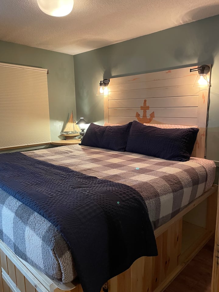 Lit king size. Remarque : le lit est sur mesure - construit avec un rangement en dessous pour votre utilisation, mais cela le rend plus élevé qu'un lit moyen. Il y a un tabouret d'escalier si vous avez besoin d'un coup de pouce supplémentaire !
