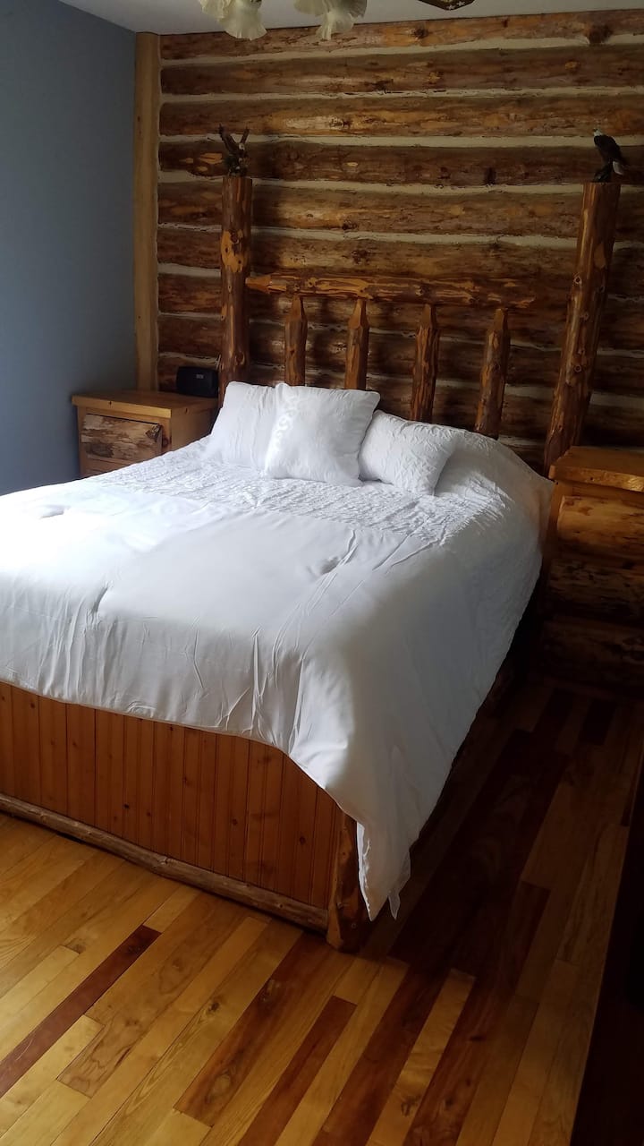 El dormitorio del piso principal cuenta con una cama de tronco grande hecha a mano.