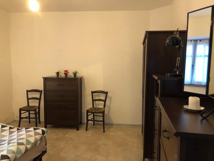 Downstairs bedroom with three dressers, a closet, a queen size bed, two chairs, and two nightstands.