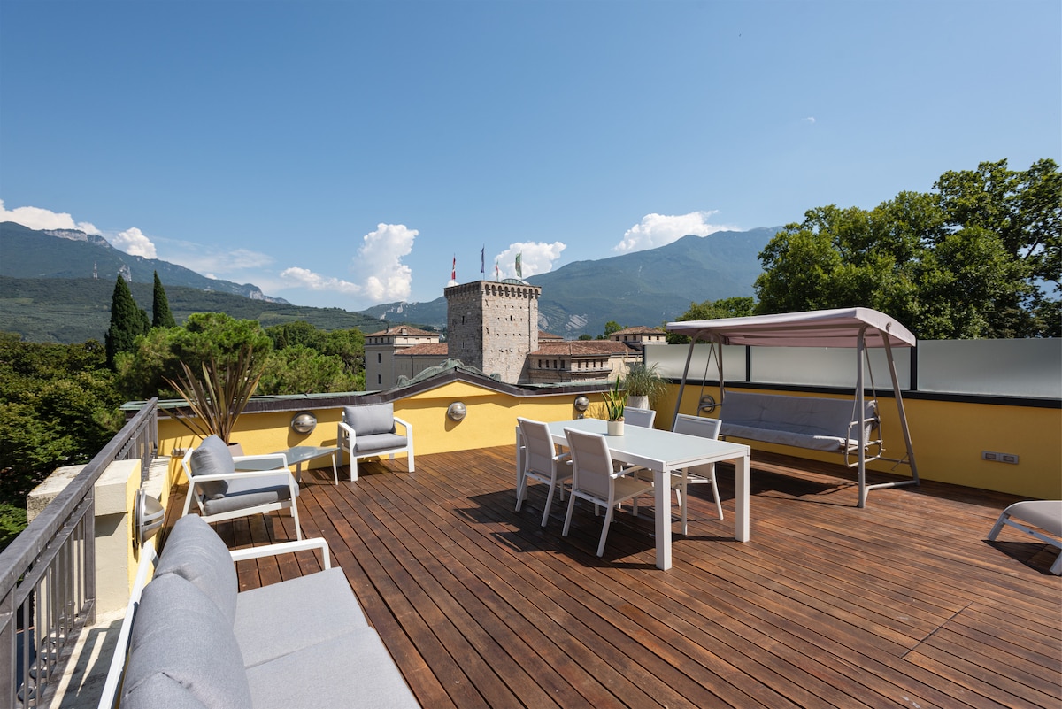 A spacious terrace is featured, showcasing wooden decking and various seating options. A dining table is set for gatherings, complemented by lounge areas. Views of lush greenery and distant mountains are visible, creating a serene outdoor space suitable for relaxation.