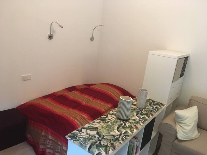 Zona para dormir en la sala de estar con cama matrimonial (1,40m x 2,00m) 
Separación del salón de descanso junto a los estantes.