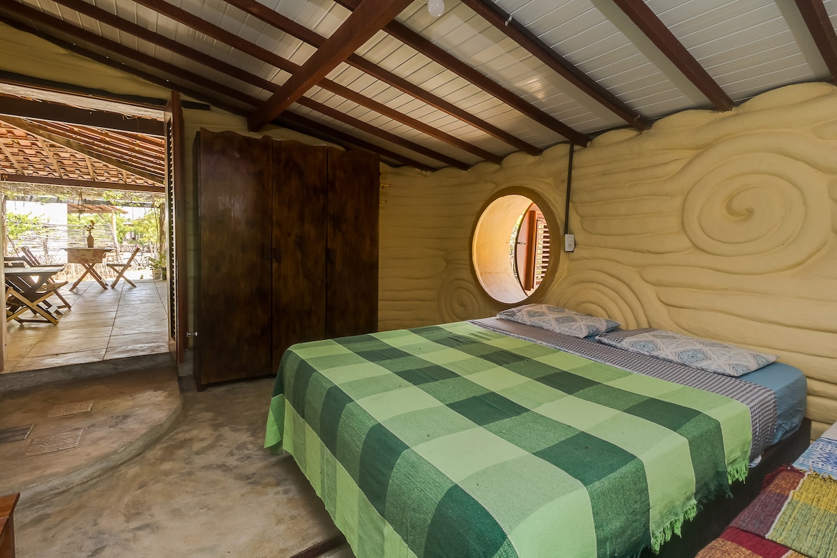 Suite "Terra", cuenta con una queen y una cama individual, baño con mosaico artístico y puerta con entrada independiente a la casa y otra que se comunica con la sala 