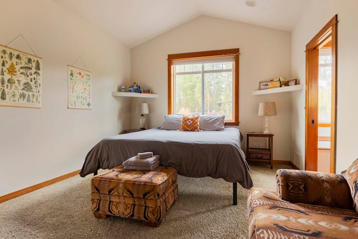 Kitanda cha ukubwa wa King katika chumba cha msingi kilicho na mabango ya kupendeza ya asili na dirisha kubwa linaloangalia ua wa nyuma. 