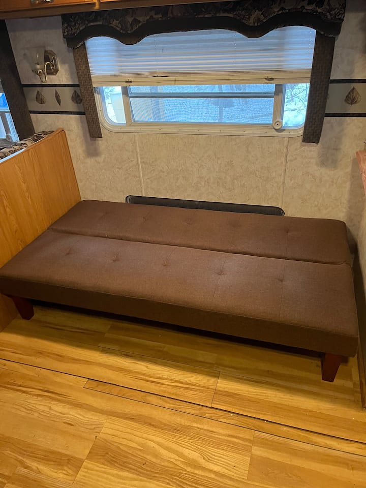 Interior futon folds down as a single bed. This interior space offers fans, air conditioning, and propane furnace. 