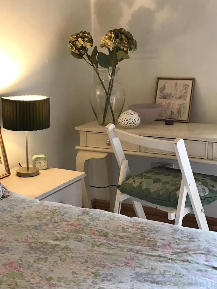 Hiki ni chumba cha kulala chenye mwanga na hewa safi chenye mihimili ya awali ya dari. Kuna meza ya kuvaa na sehemu kubwa ya kabati la nguo. 