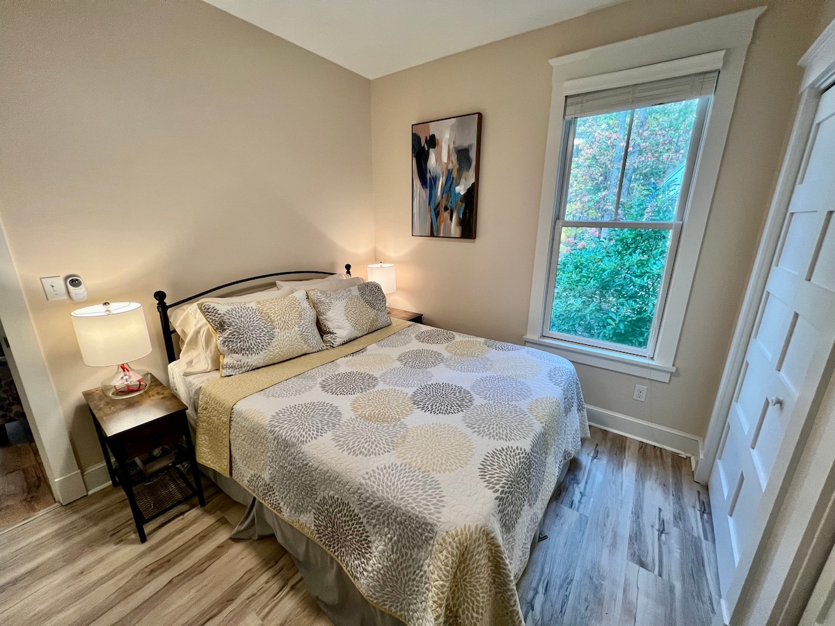 The guest bedroom, featuring a queen-size bed, dresser, smart TV with all of the apps, a desk, closet, and ceiling fan. 
