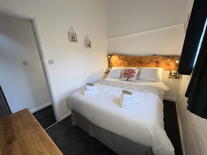 Მთავარი საძინებელი, ორადგილიანი საწოლი განსაცვიფრებელი Yew-ის თავსაფრით და უჯრისა და ტელევიზორის გულმკერდით.