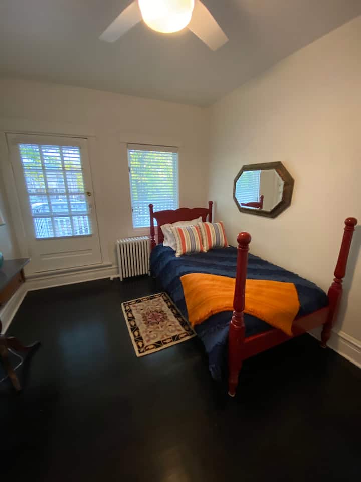 Მობინადრეების ოთახი. 1 ორსაწოლიანი საწოლი და ხის მოპირკეთებული აივანი ბისტრო მაგიდით და სკამებით.