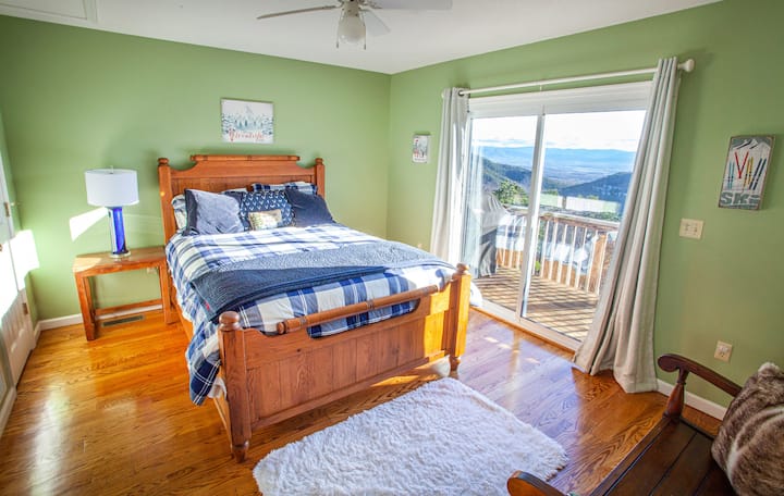 Second master bedroom on the top floor with stunning mountain views and direct deck access. Features a private ensuite bathroom and a wall-mounted TV, creating a cozy and convenient space for your stay.