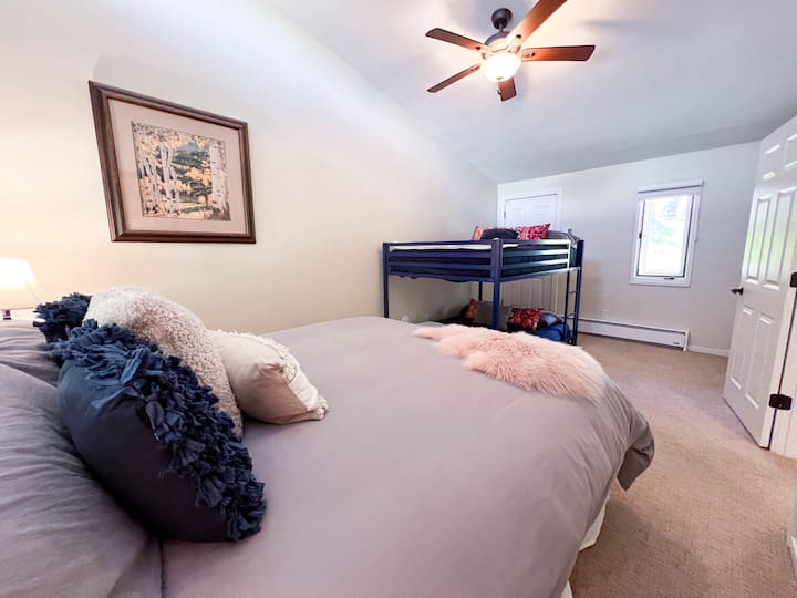 A large bedroom with a King bed and bunk bed with two full mattresses.