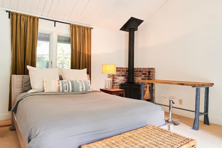 Serene master suite with Tuft & Needle Mint queen, W Hotels down featherbed and premium linens. Warm lighting creates a cozy retreat atmosphere.  Bedroom features a private forest outlook and deck access through sliding glass doors opposite the bed