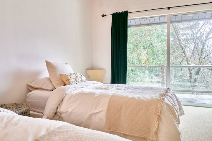 Private forest outlook and deck access through sliding glass doors.  Natural light streams through forest-facing windows.