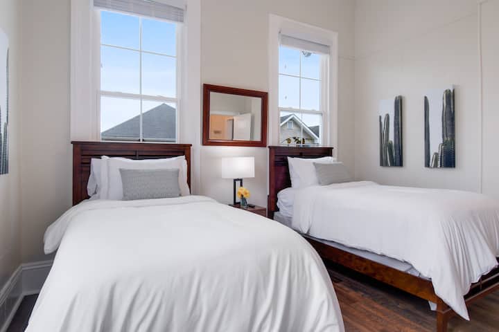 ห้องพักโปร่งสว่างสดใสพร้อมเตียงแฝด 2 หลังพร้อมพัดลมเพดาน ห้องนี้ไม่มีผ้าม่าน 