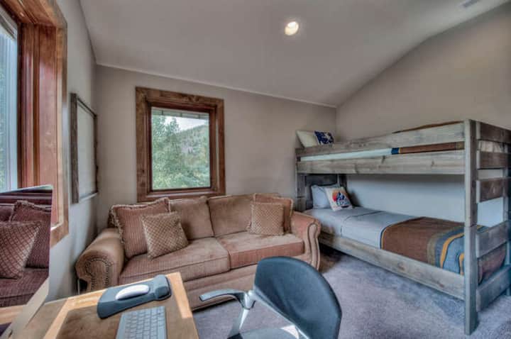双层床房，配有沙发床、电视和小办公桌区域。