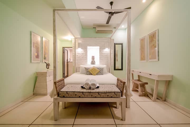 Serene bedroom w/ canopy bed, soft lighting & calming pastel tones throughout
