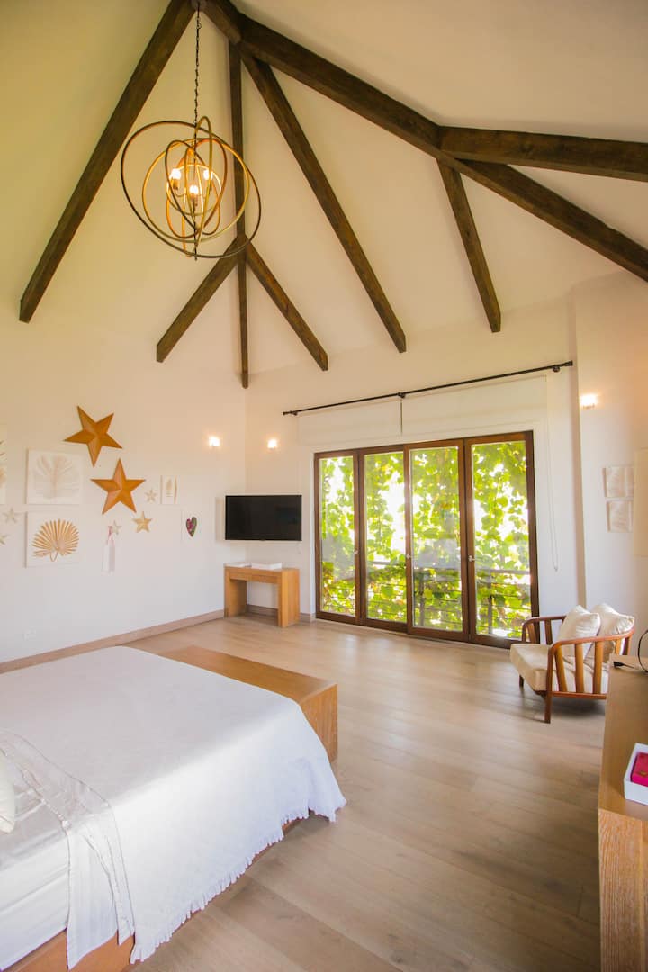 Dhomë gjumi kryesore me tavane të larta, dekor elegant dhe hyrje në ballkon. Dritaret e gjera ofrojnë pamje spektakolare dhe ventilim të shkëlqyer.