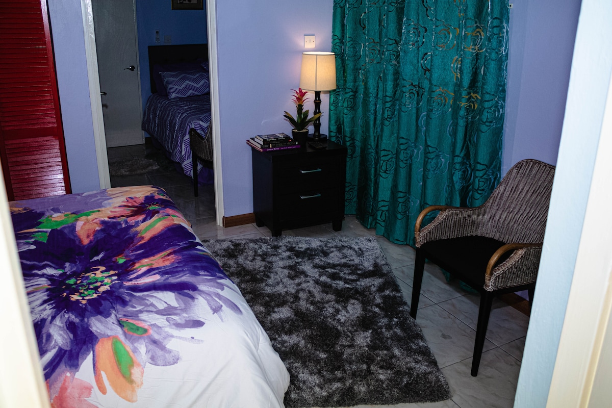 Спална соба 2 се граничи со спалната соба 1. И двете имаат мала маса, ламба, книги и стол.