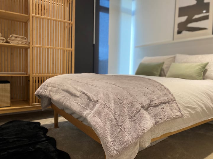 غرفة نوم ثانية بسرير مزدوج مريح، وستارة سوداء، وفراش فاخر ومناشف ناعمة.
